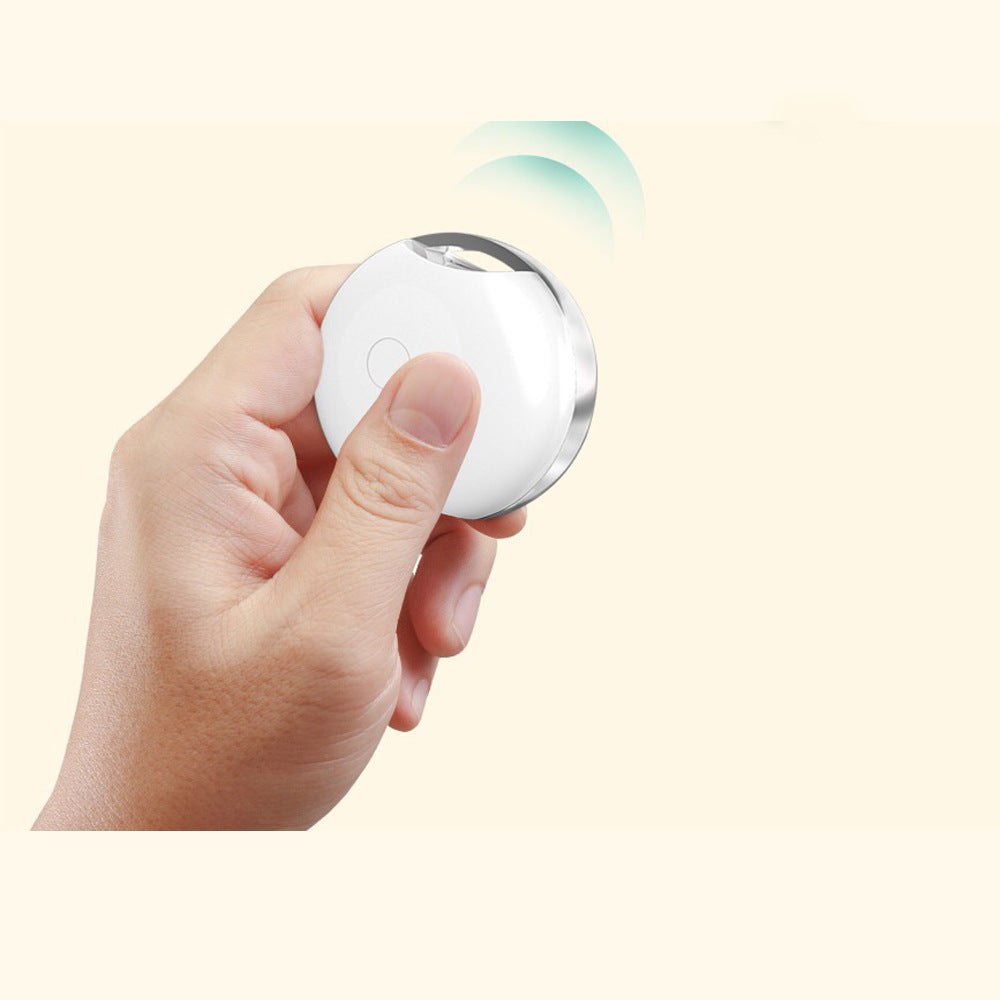Hand holding a white round device with a light on a beige background